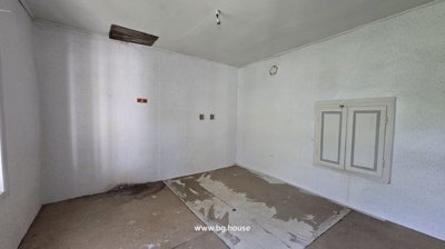 An indoor room featuring unfinished plaster walls, a tiled floor, and a wooden ceiling.