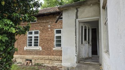 White wooden door open from the garden side into the house, showing part of the brick and plaster exterior walls.