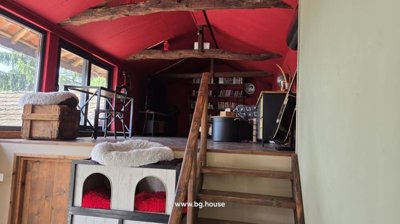 Upper floor room with red painted walls, wooden floor, bookshelves, and a cozy seating area with cushions and a small table.