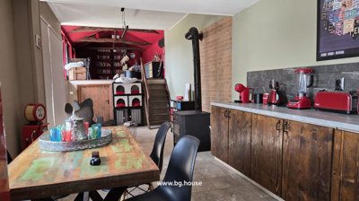 Interior view of kitchen and dining area featuring wooden cabinets, a wood stove, and a colorful dining table with chairs.