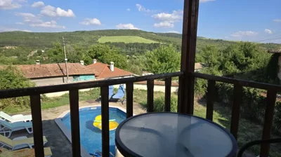 View of the swimming pool and surrounding stone patio with lounge chairs and garden greenery.