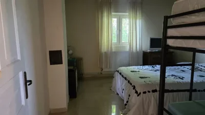 Bedroom containing a double bed, a metal bunk bed, window with curtains, and a radiator beneath the window.