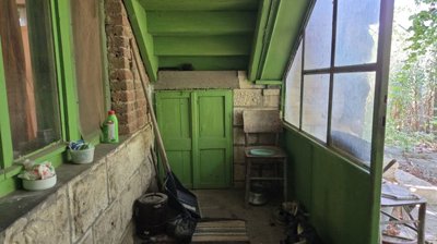 Green painted porch area featuring a window and assorted household items