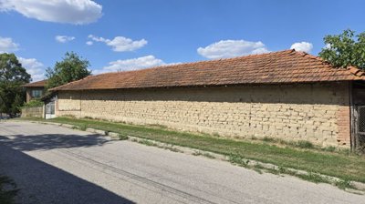 Side view of a long brick outbuilding with tiled roof and metal gate at one end
