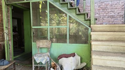 Green painted porch area with a chair and stairs ascending to upper floor