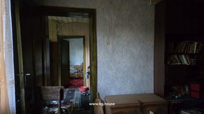 Interior view showing a chair, wooden chest, and floral wallpaper through multiple doorways