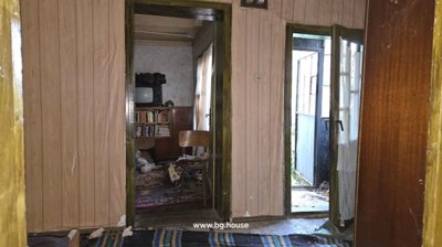 Room featuring two doorways, a wooden chair, and walls with peeling wallpaper