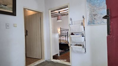 Indoor view through doorway showing bedroom with metal bed frame and wooden floor.