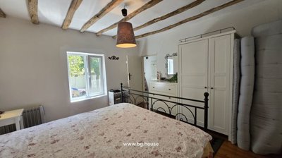 Bedroom showing a black metal bed frame, white wardrobe, window with natural light, and rolled mattresses
