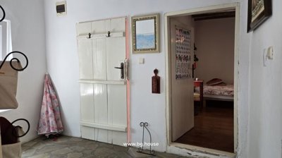 Hallway with white walls, exposed wooden ceiling beams, stone flooring, and open doorways to adjacent rooms