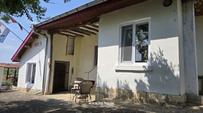 Outdoor courtyard with white walls, tiled roof, and small table with chairs in shaded area.