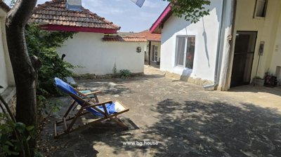 View of outdoor courtyard featuring white walls, tiled roof, and a lounge chair with blue towel.