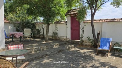 Outdoor courtyard showing white walls, tiled roof, small table with chairs, and barbecue grill.