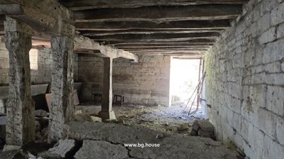 Stone cellar room with wooden beams and an open doorway leading outside.