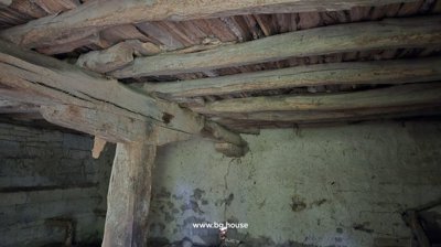 Stone cellar interior featuring wooden ceiling beams and rough stone walls.
