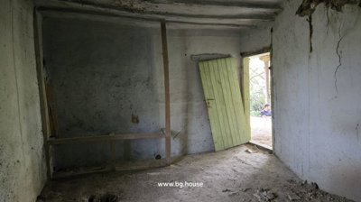 Interior room with bare walls and a wooden door leaning open to the outside.