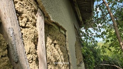 Close-up view of a house wall featuring mud and timber construction with plaster repairs.