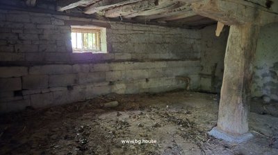 Stone cellar interior showing wooden beams and a dirt floor.