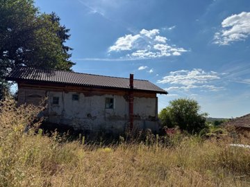 Rear facade of the old Bulgarian house with plastered walls and small windows.
