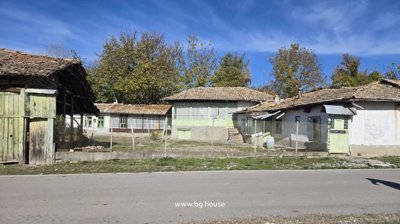 Front view of a traditional Bulgarian house with multiple tiled roofs and a fenced yard in Kovachevets village