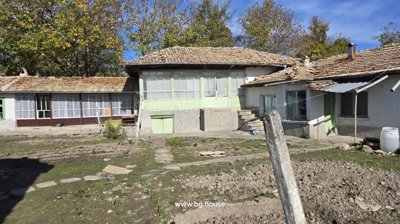Rear exterior of the Bulgarian house showing an enclosed porch with large windows and adjacent garden area
