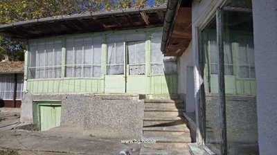Enclosed veranda with green wooden framed windows and steps leading up to the entrance in Kovachevets village house.