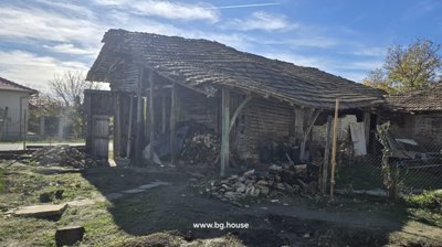 Rustic wooden barn with open sides and tiled roof, used for storage in the village property yard