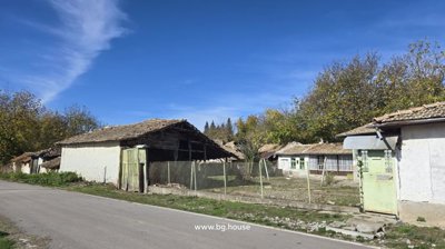 Wide angle view of the village property including a wooden barn, fenced yard, and several connected buildings