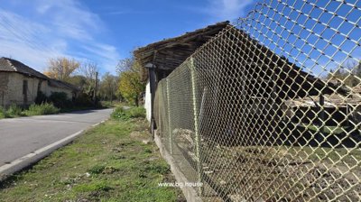 Chain link fence enclosing the village property including barn and outbuildings along a paved road
