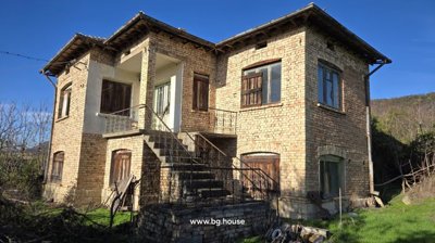 Exterior view of a two-storey brick house featuring wooden shutters and an iron-railed external staircase.