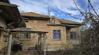 Exterior of a traditional Bulgarian house showing brick walls, tiled roof, and wooden window frames.