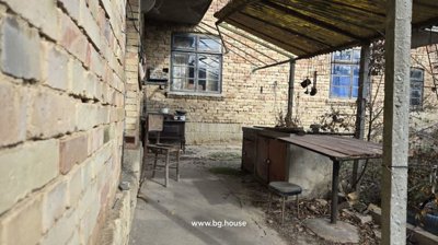 Outdoor covered area featuring a wooden chair, old stove, and brick walls under a translucent roof.
