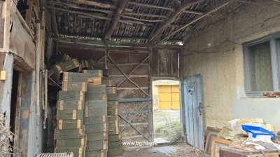 Interior of a covered storage space showing stacked wooden crates and an open door to the outside