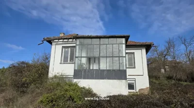 Front exterior of a white two-storey house featuring a glass-enclosed balcony and tiled roof
