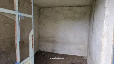 Interior view of a small unfinished room with rough plastered walls and a metal door frame