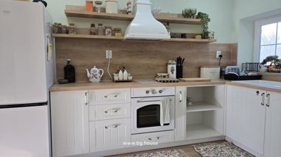 Kitchen counter with white cabinetry, oven, and open wooden shelves displaying kitchenware and decorative items.