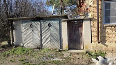 Close-up of wooden garage doors and a brown entrance door attached to a brick house, with dogs nearby.