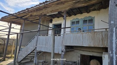 Exterior view showing an upper floor balcony with wooden posts and a metal railing
