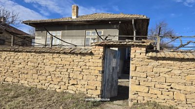 Open wooden gate in stone wall with stairs leading up to house entrance