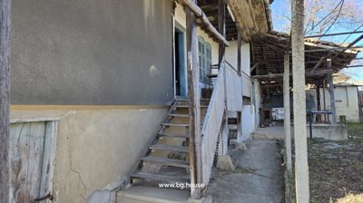 Side perspective of house stairs and porch area with wooden posts and chairs