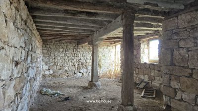 Large interior space with stone walls and two central pillars supporting wooden ceiling beams.