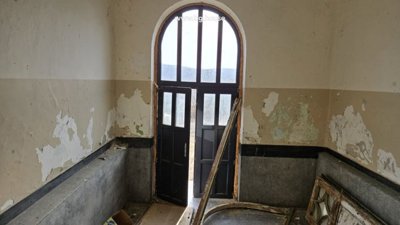 Doorway inside the school featuring a tall arched window and aged wall surfaces