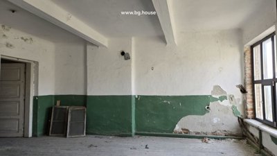 Interior room featuring white and green walls with peeling paint, wooden floor, and a large window