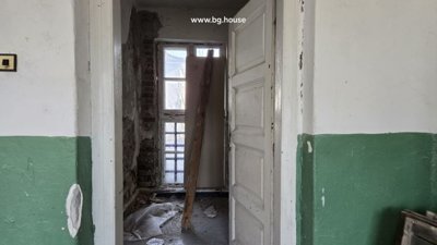 Interior room with peeling white and green walls and a window overlooking the outdoors