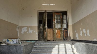 Hallway inside the school showing aged walls and open double wooden doors