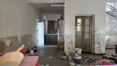 Room inside the school showing worn walls, scattered objects, and wooden doors