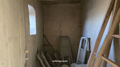 A small interior room used for storage with old doors, window, and various items leaning against the wall.