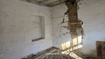 Interior corner showing cracked plaster walls and a small recessed window opening.
