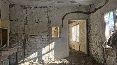 A rustic interior room with stone and plaster walls, featuring an old wooden cabinet on a table.