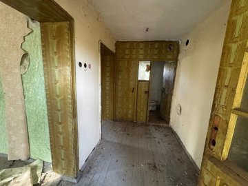 Interior hallway showing wooden floor, yellow walls, and open door revealing bathroom with toilet